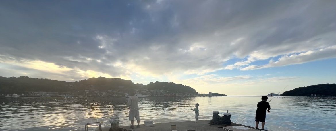夕方の海辺の釣り場で、釣りを楽しむ家族のシルエット